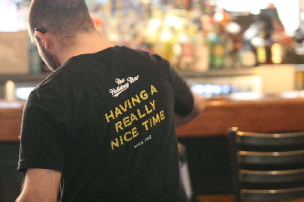 Man wearing "Having a Really Nice Time" T-shirt at a bar or cafe.