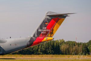 Aeroporto di un aereo militare con decorazioni speciali per l'Air Defender 2023, con un paesaggio di campagna e alberi sullo sfondo.