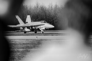 F-18 from Finland F-18 fighter jet on runway viewed through a blurred frame in a black-and-white photo.
