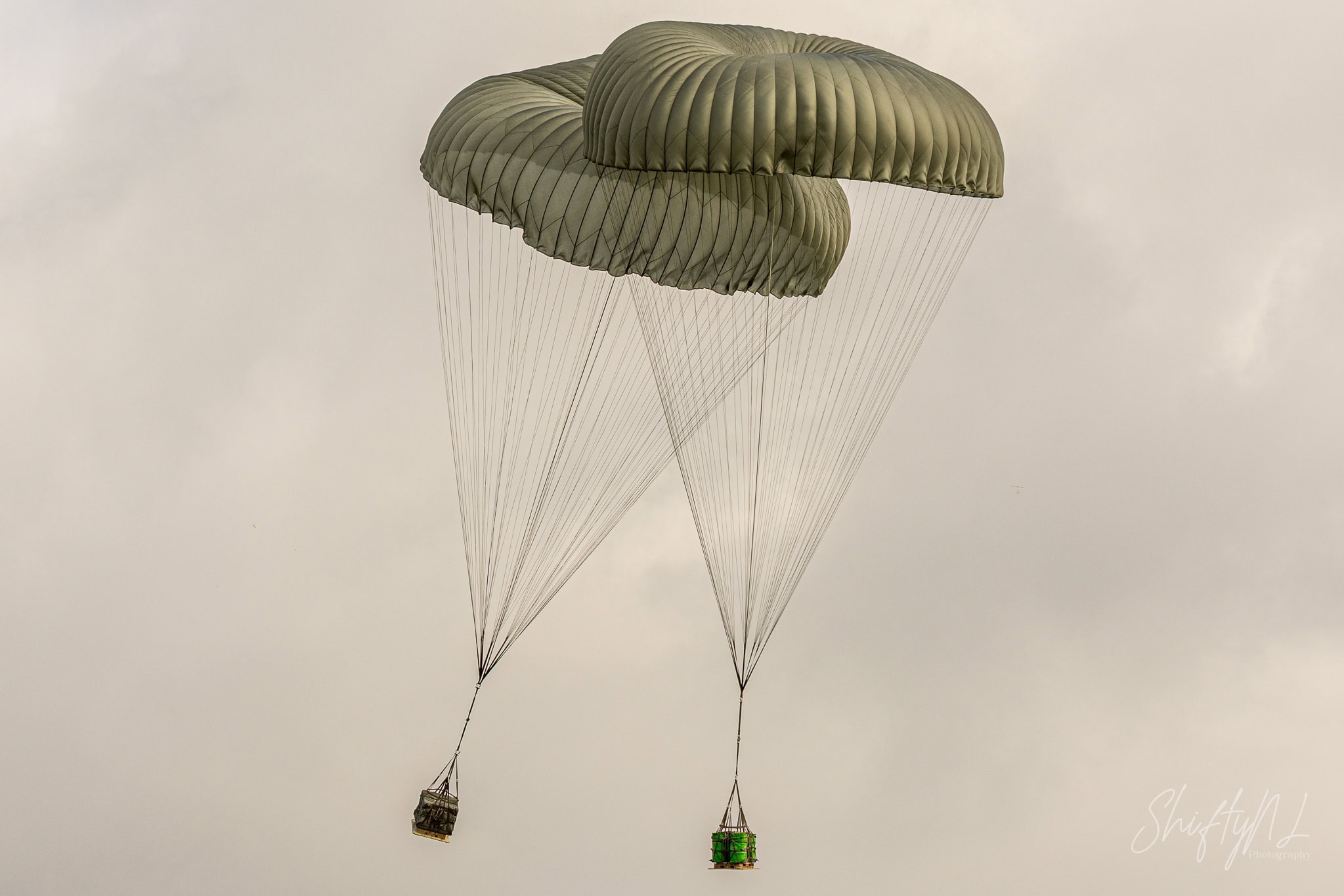 Two supply pallets floating down under large green cargo parachutes at Deelen, during exercise Falcon Autumn, the Netherlands, October 2018.