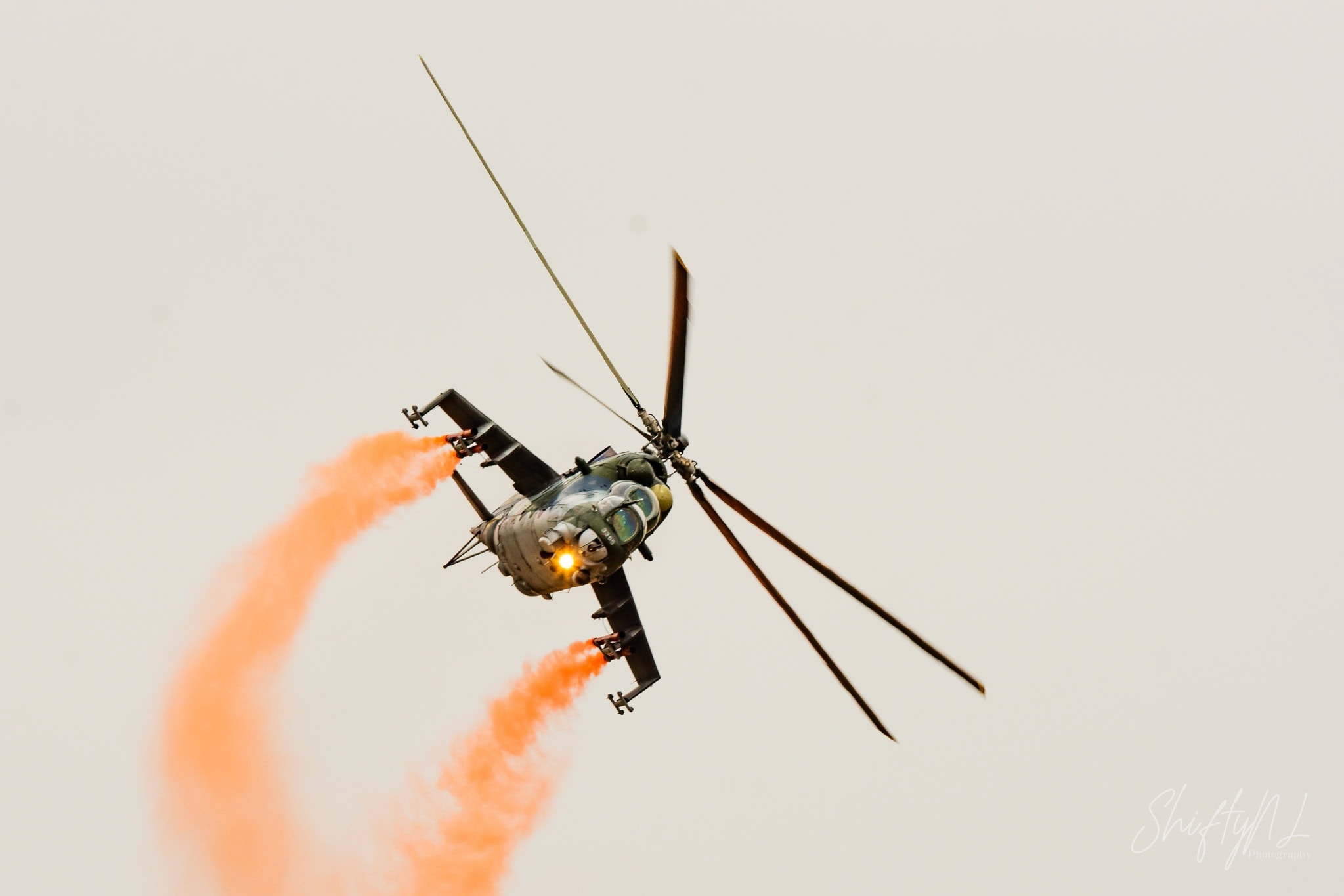 Mi-24 Smoke Turn Czech Air Force Mi-24 Hind in a steep turn trailing orange smoke from its wing pylons at the Leaseweb Texel Airshow, Texel International Airport, the Netherlands, August 2018.