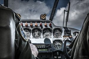 Old plane instruments cockpit van een vintage vliegtuig met analoge meters en besturing onder een bewolkte hemel.