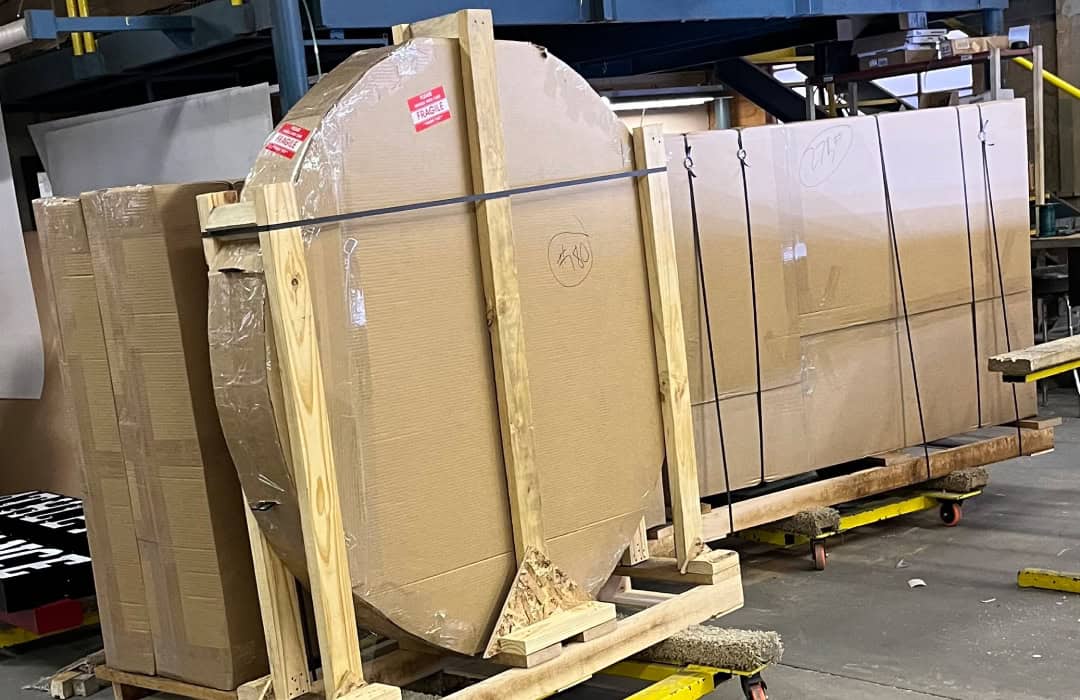 Large circular glass sheet secured on a wooden pallet in a manufacturing warehouse.