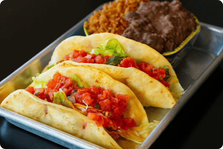 Savory tacos with fresh lettuce and tomato, seasoned rice, and hearty beef in a metal tray at Smokey Jose's.