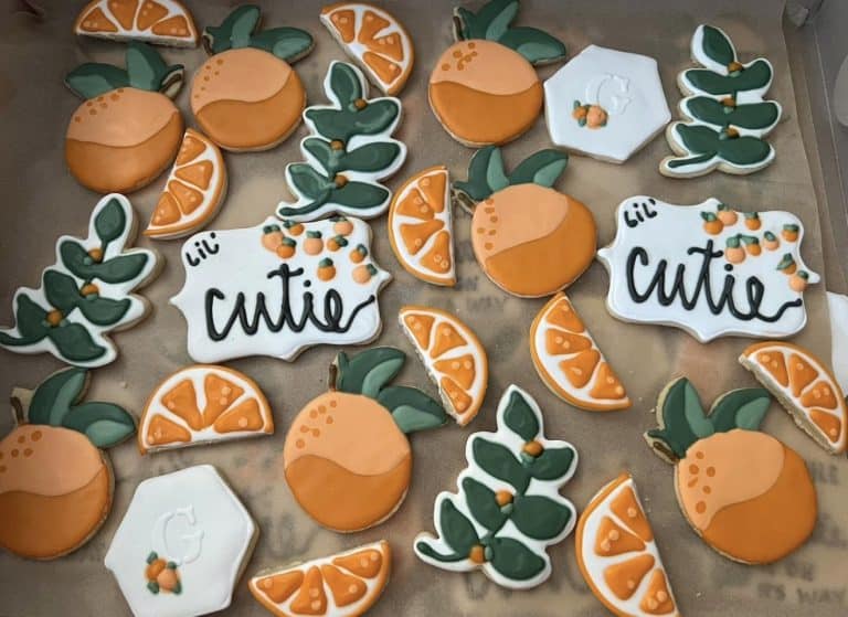 Decorative cookies shaped like oranges, leaves, and the words 'Lil Cutie' for bakery display.
