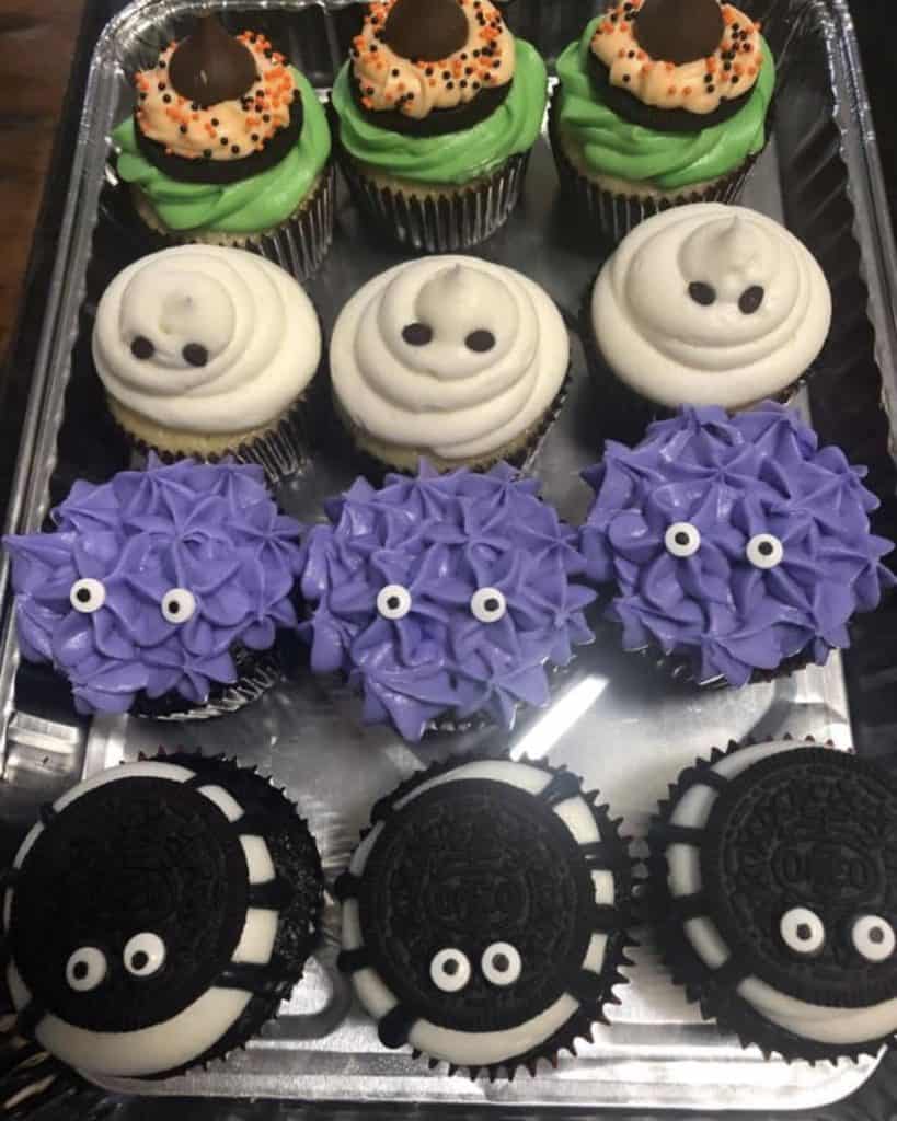 Assorted Halloween-themed cupcakes with colorful frosting and spooky decorations.