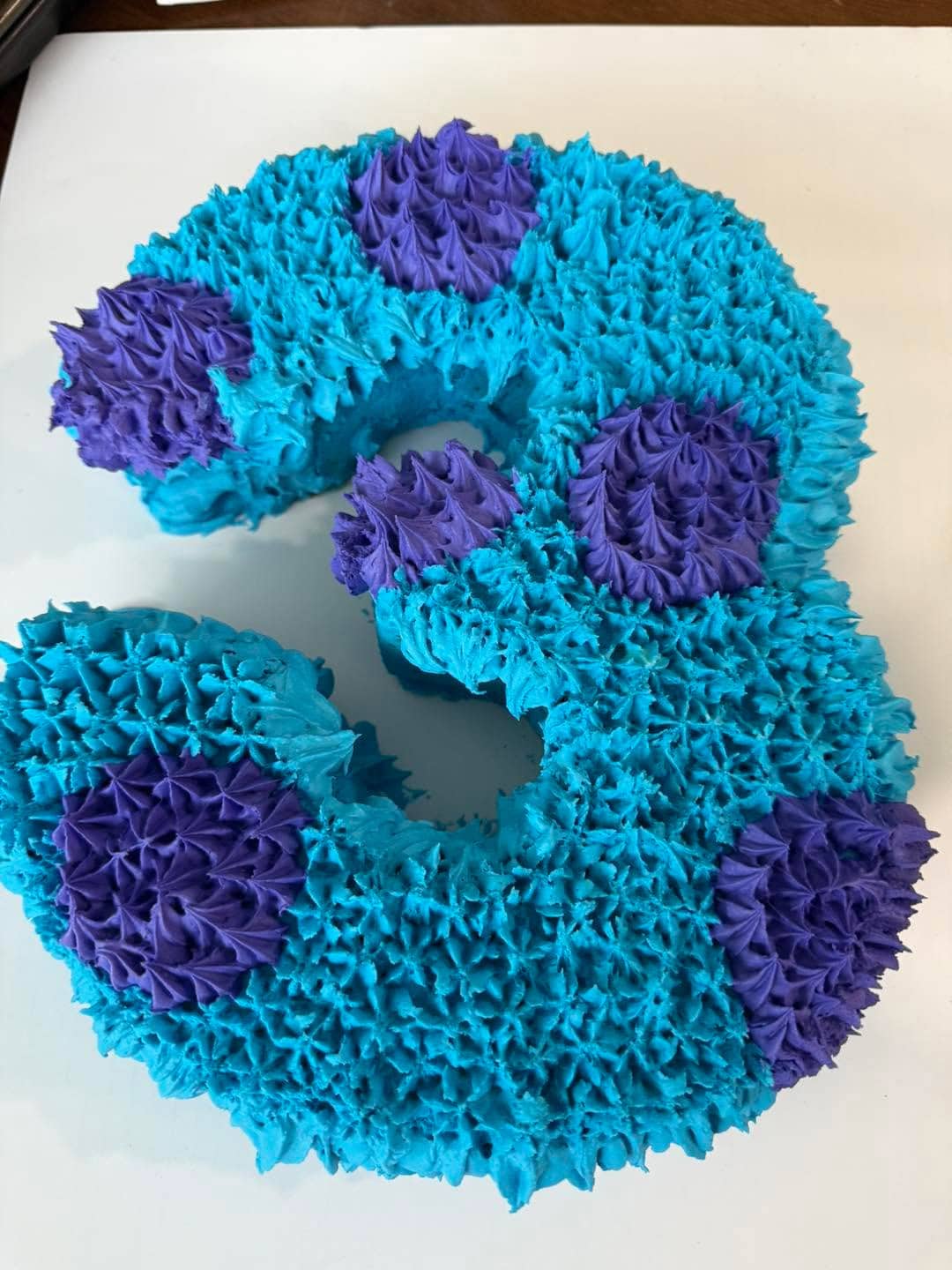 Colorful number 9 cake with blue and purple frosting for celebration.