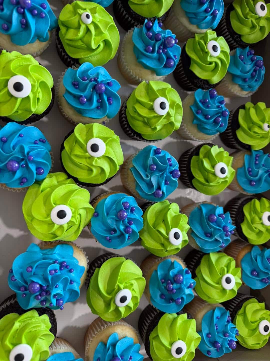 Colorful cupcakes with green and blue frosting and eye decorations.