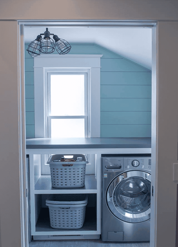 Modern laundry room with washer, baskets, and window.