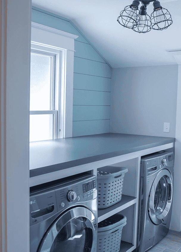 Modern laundry room with washer, dryer, and storage shelves under a skylight.