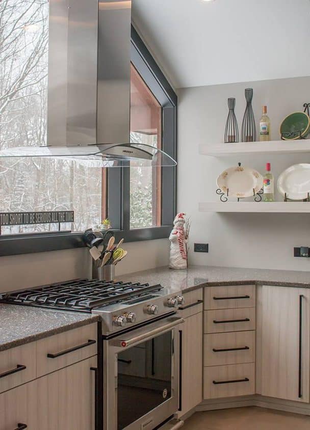 Contemporary kitchen with large window, stove, and open shelving.