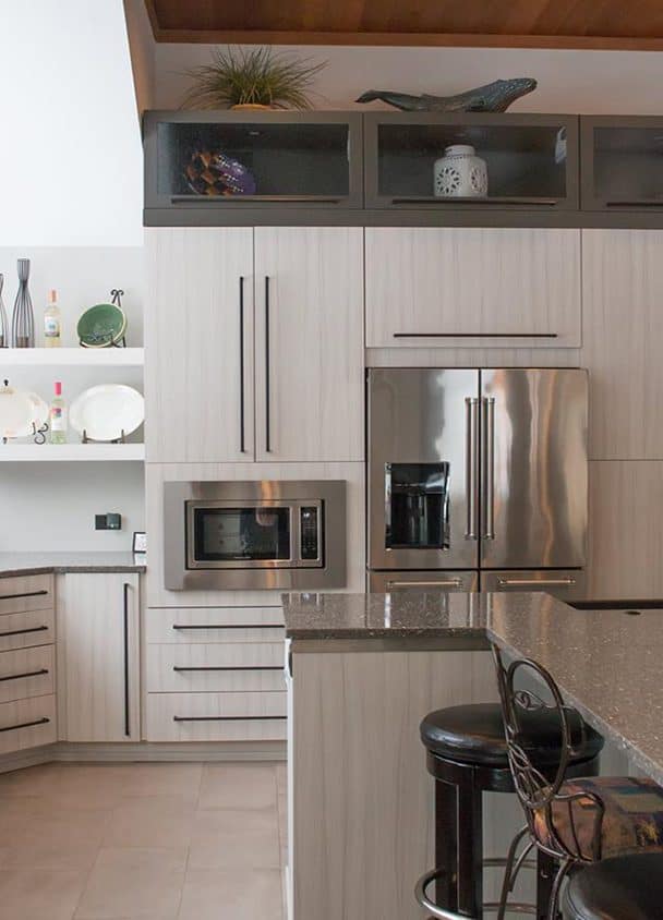 Contemporary kitchen with stainless steel refrigerator and light wood cabinets.
