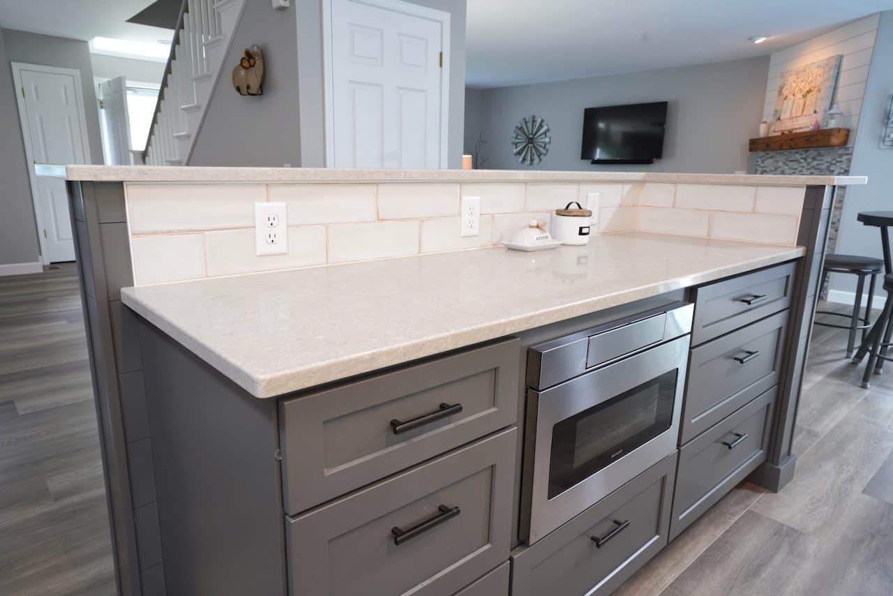 Kitchen island with gray cabinets and built-in microwave oven.