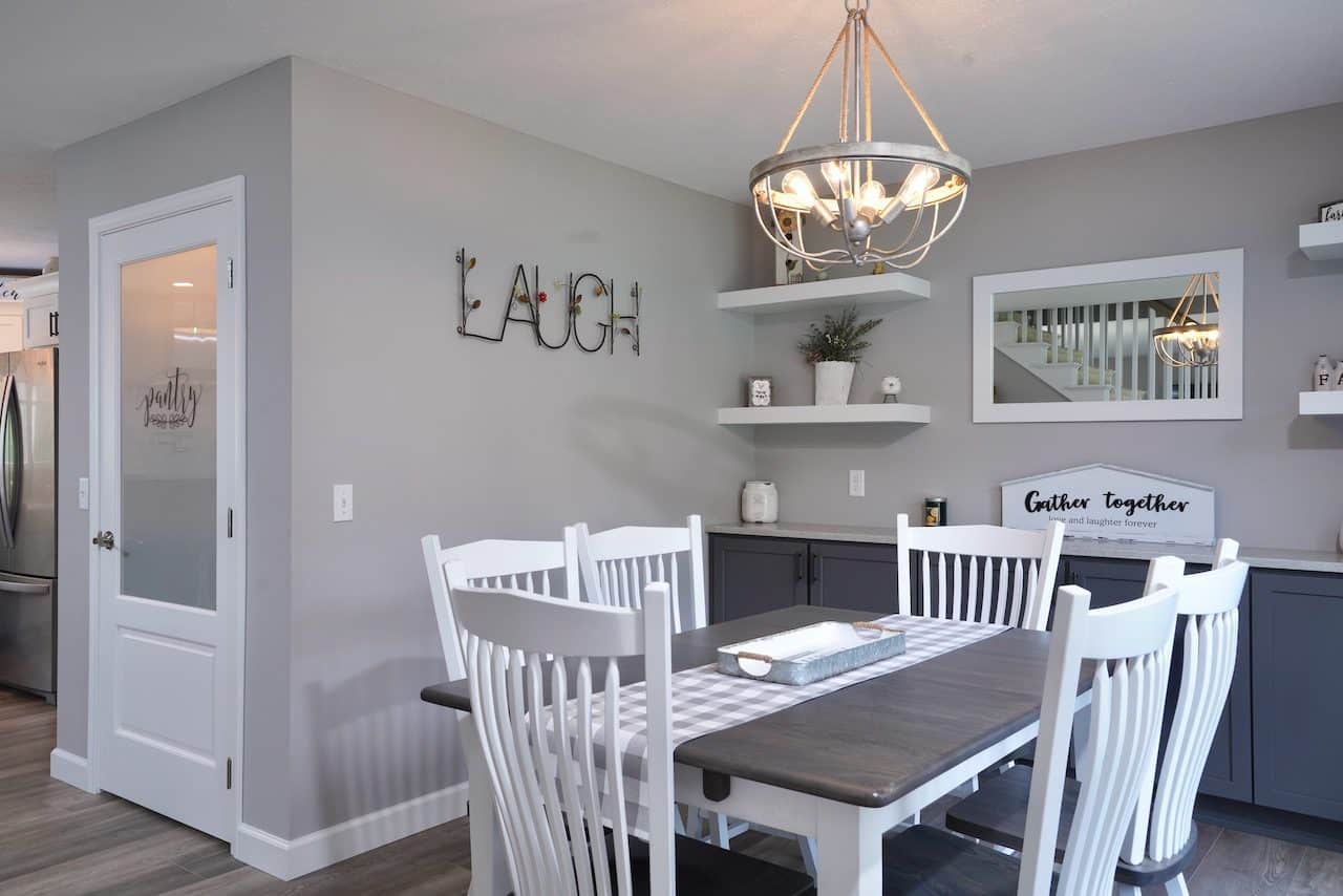 Contemporary dining room with white chairs, gray walls, and decorative wall art.