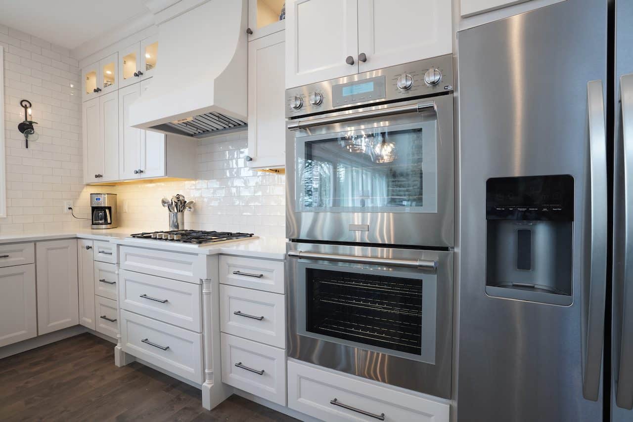 Contemporary kitchen with white cabinets, stainless steel oven, and dark wood flooring.