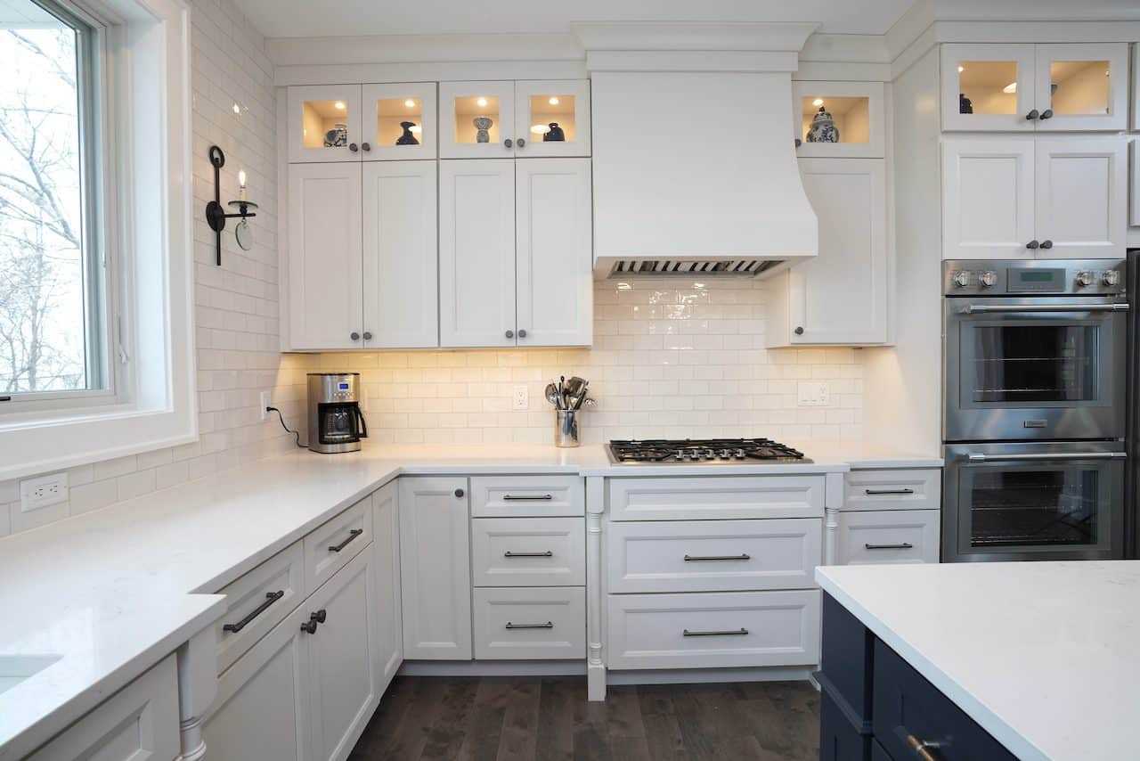 Contemporary white kitchen with built-in cabinets and stainless steel appliances.