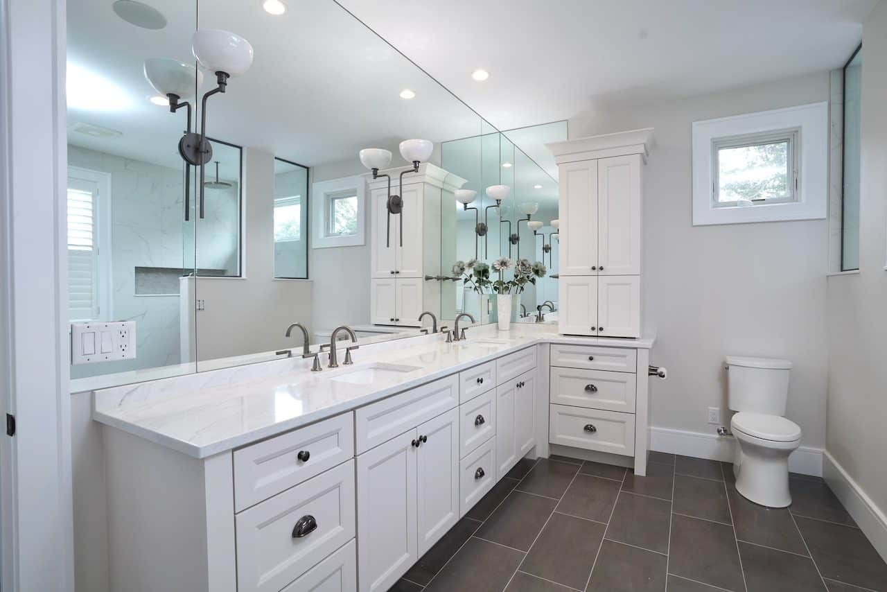 Bright bathroom with white cabinetry, double sinks, and a large mirror.