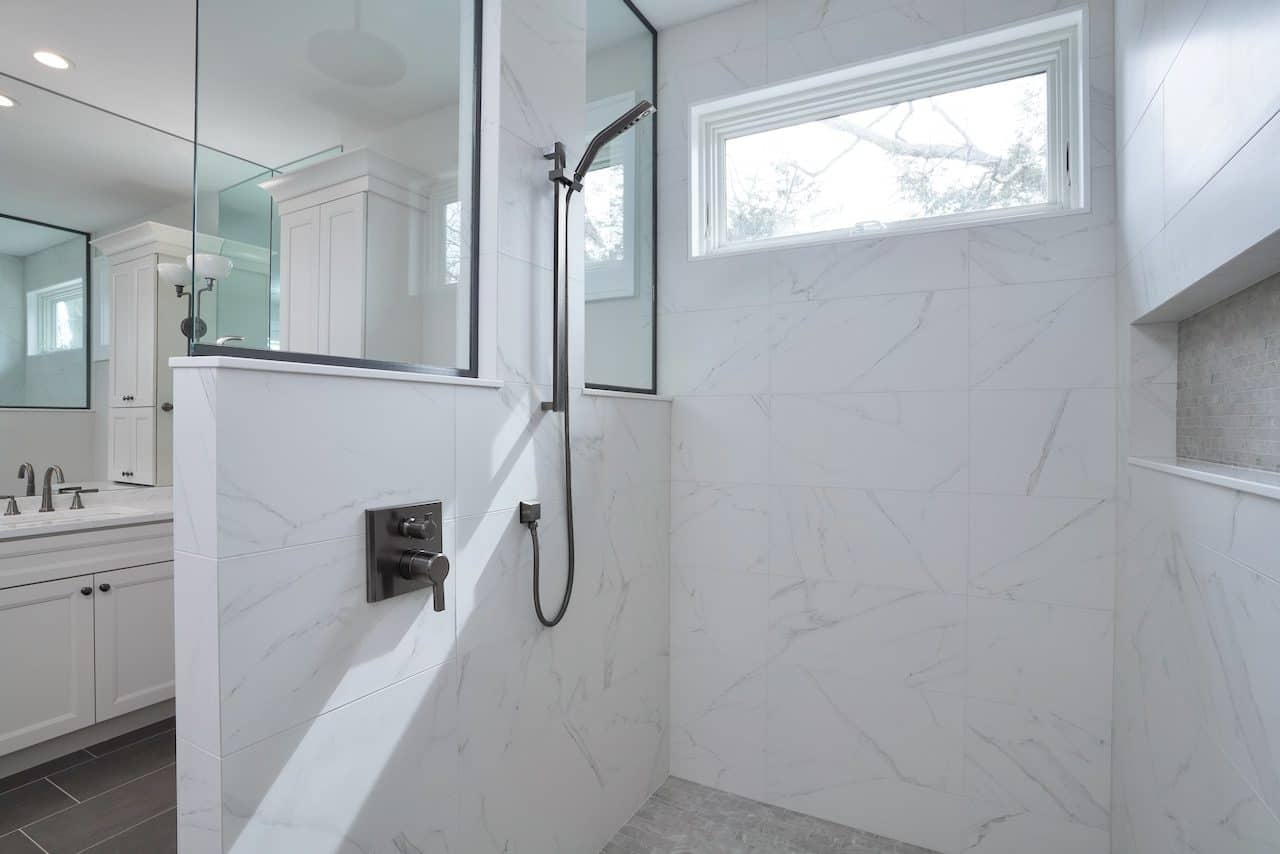 Contemporary bathroom shower with white marble walls and large window.