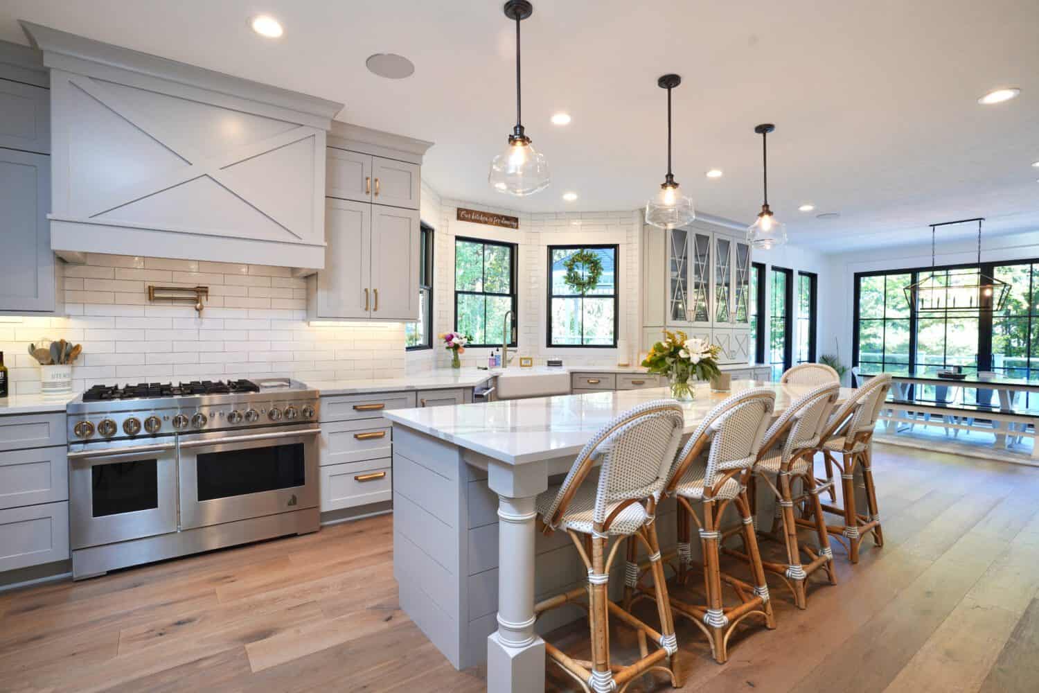Bright modern kitchen with white cabinets, island, bar stools, and pendant lighting.