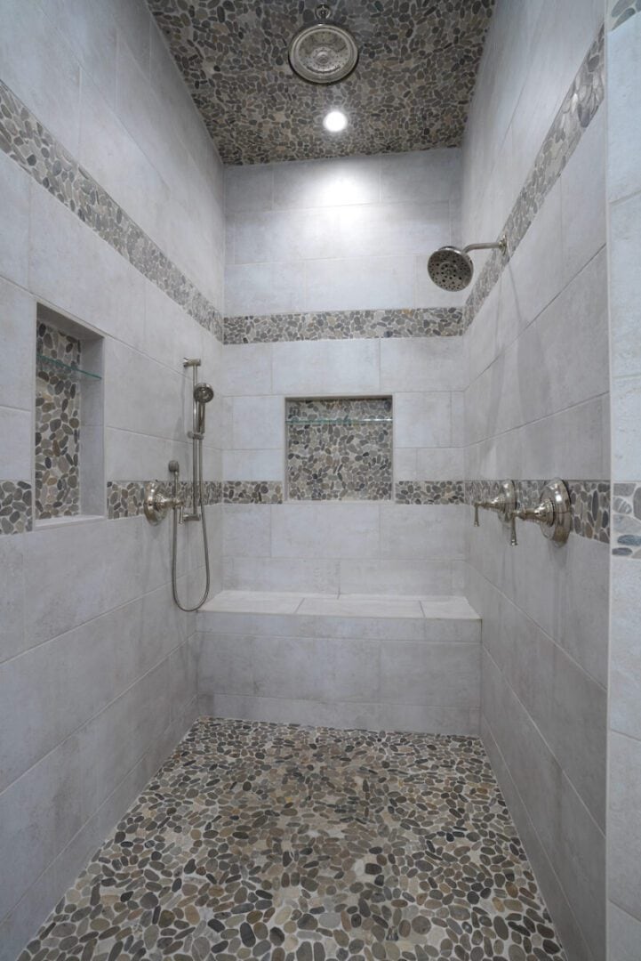 Modern walk-in shower with pebble floor and stone wall accents.