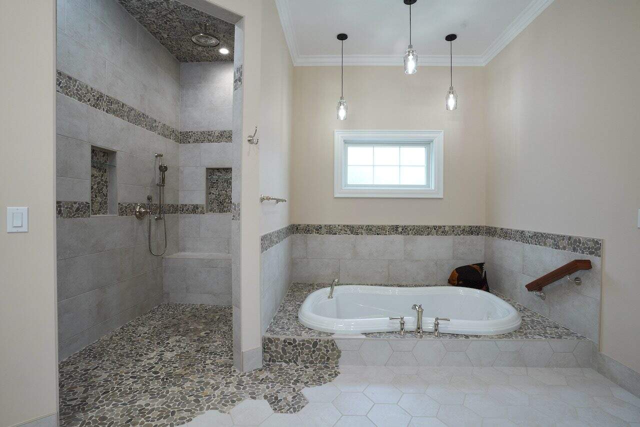 Contemporary bathroom with walk-in shower and soaking tub, neutral tones, and pendant lighting.