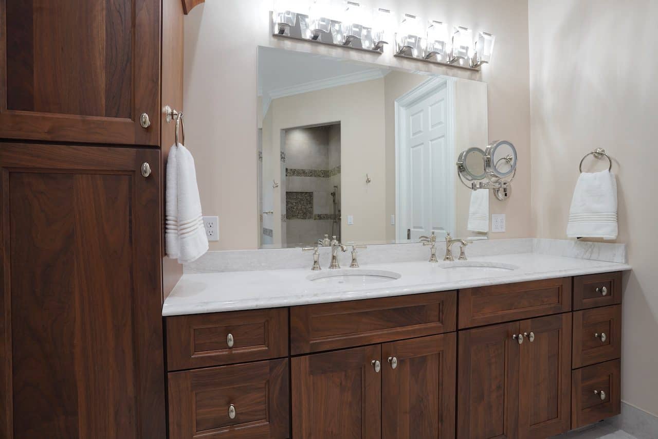 Bathroom vanity with wooden cabinets, double sinks, and large mirror.