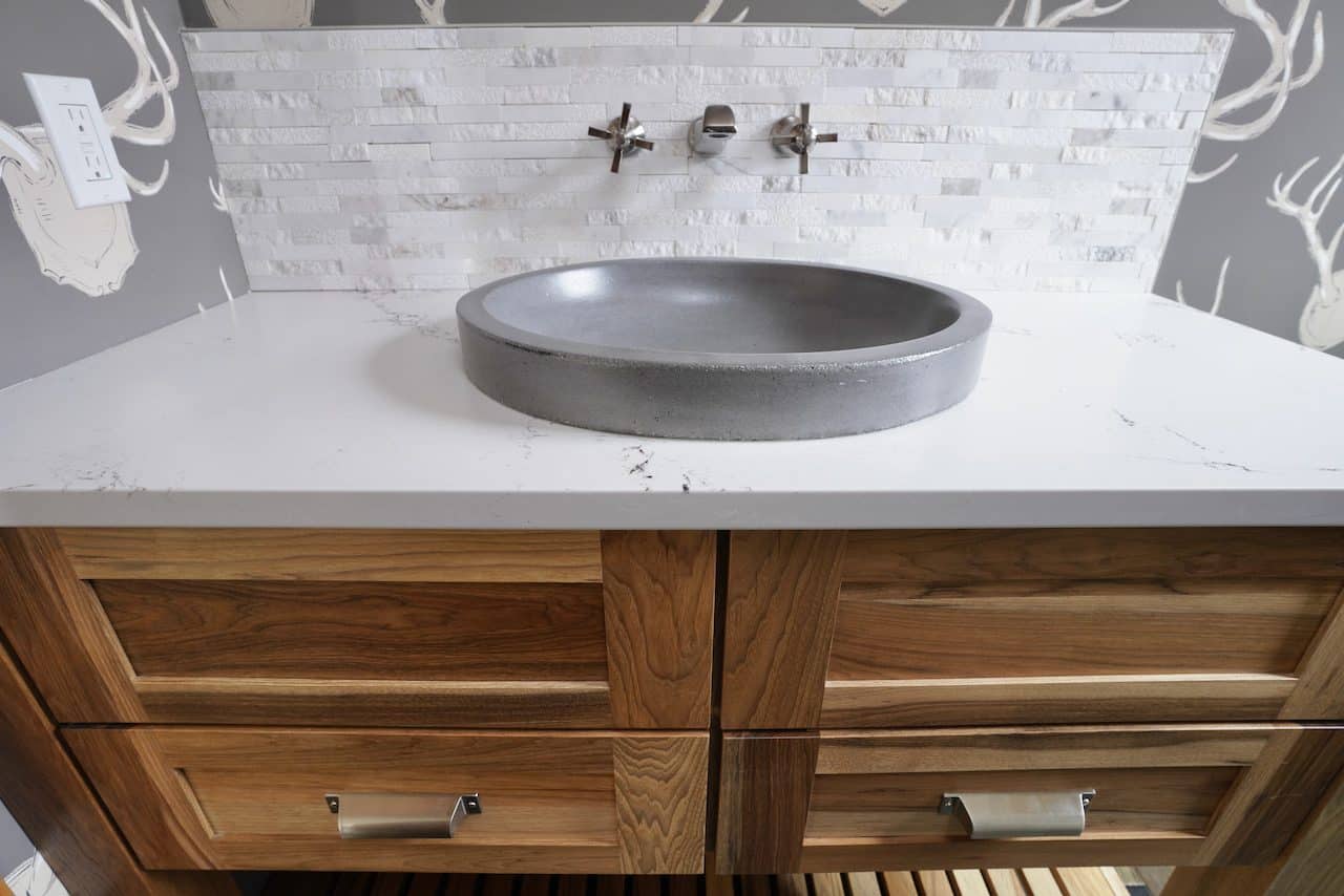 Contemporary bathroom vanity with a round stone sink and wooden cabinet.