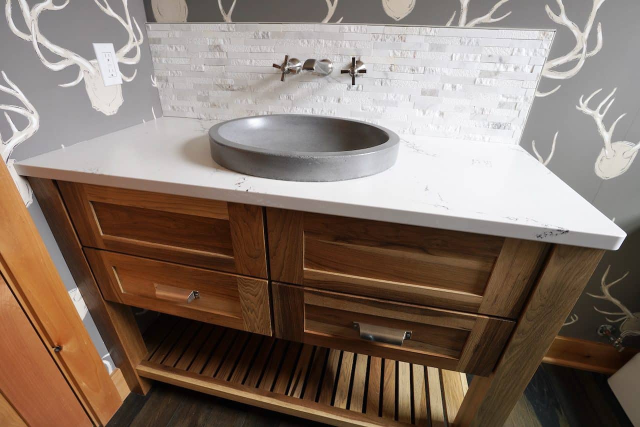 Bathroom vanity with a round stone sink and wooden drawers.