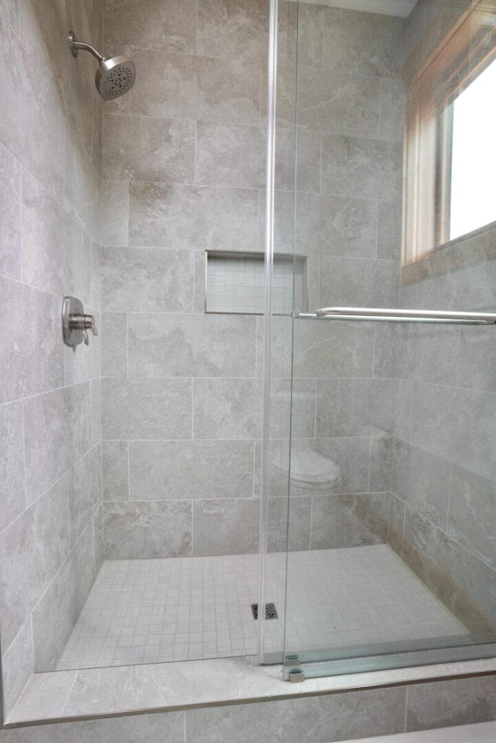 Contemporary walk-in shower with glass enclosure and tiled walls.