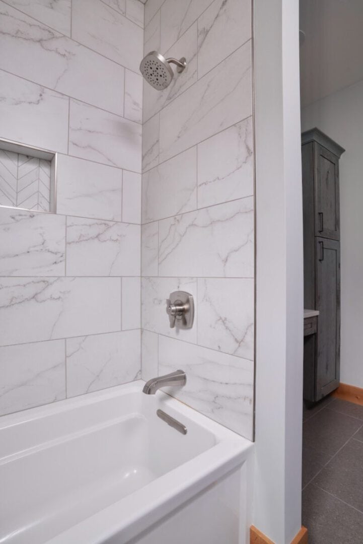 Contemporary bathroom with marble tiles, showerhead, and bathtub.
