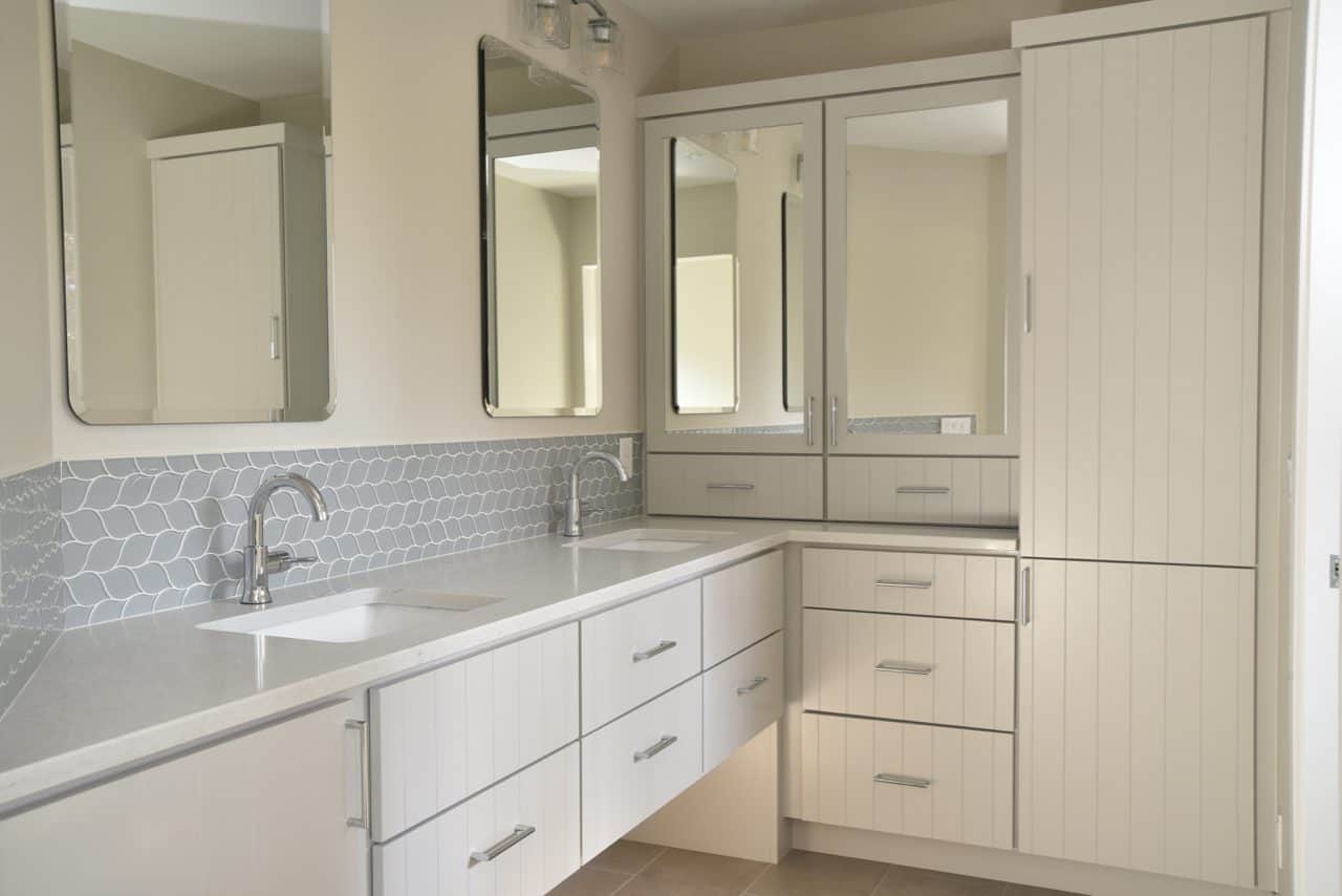 Contemporary white bathroom vanity with dual sinks and mirrored cabinets.