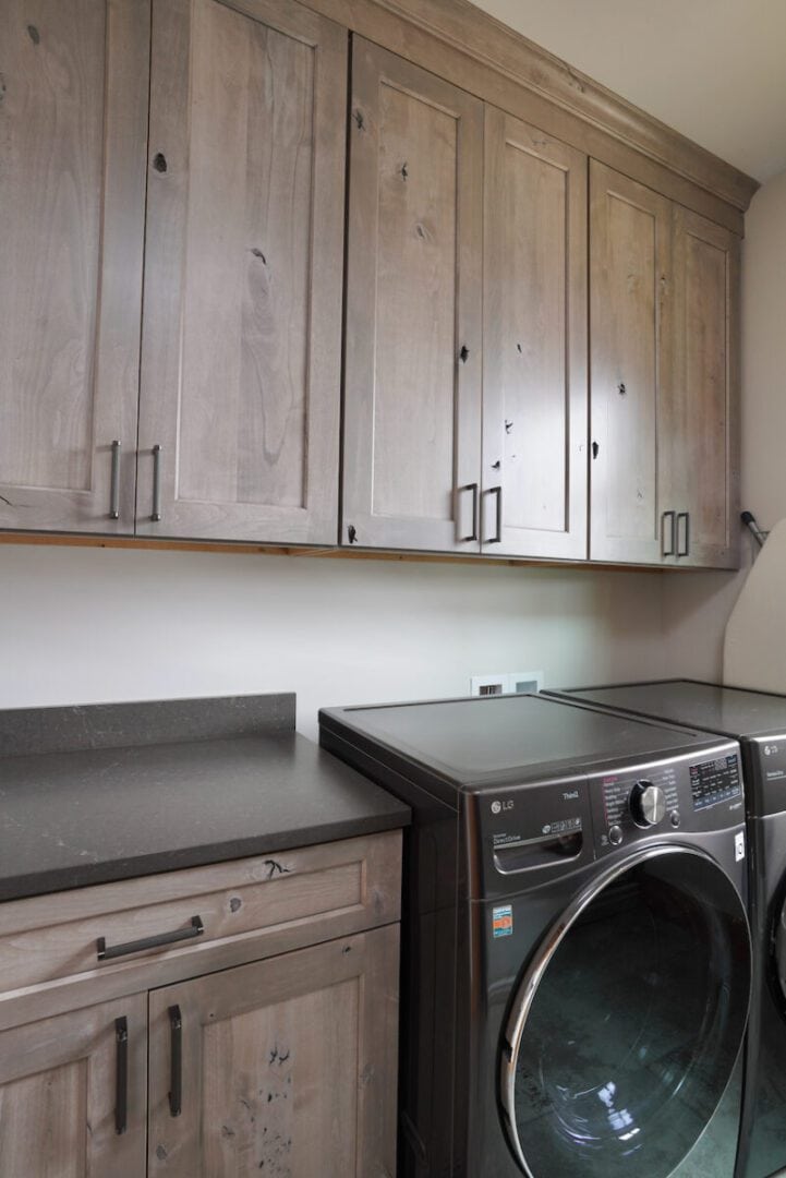 Wooden kitchen cabinets with a modern washer and dryer in laundry room.