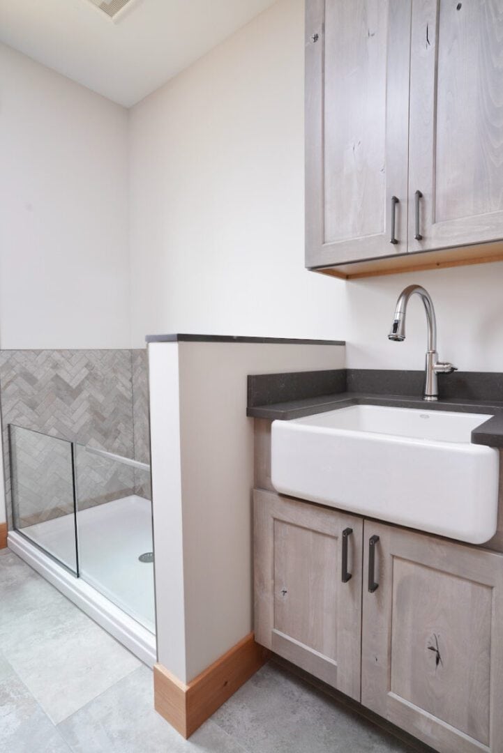 Laundry room with sink, cabinetry, and glass shower enclosure.