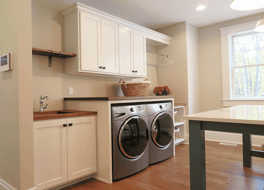 Clean laundry room with white cabinets and front-loading washer and dryer.