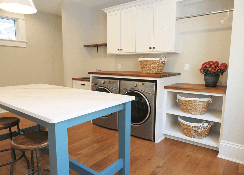 Clean laundry room with washer, dryer, and organized shelves.