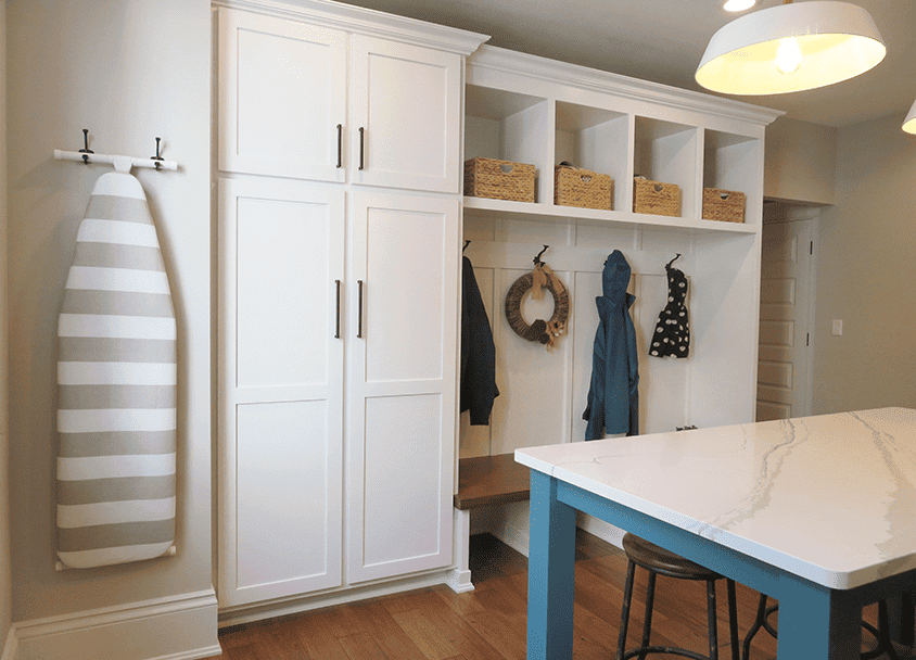 Modern mudroom with white cabinetry and hooks for coats and accessories.