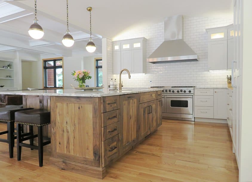 Bright white kitchen with wooden island, stainless steel appliances, and pendant lighting.
