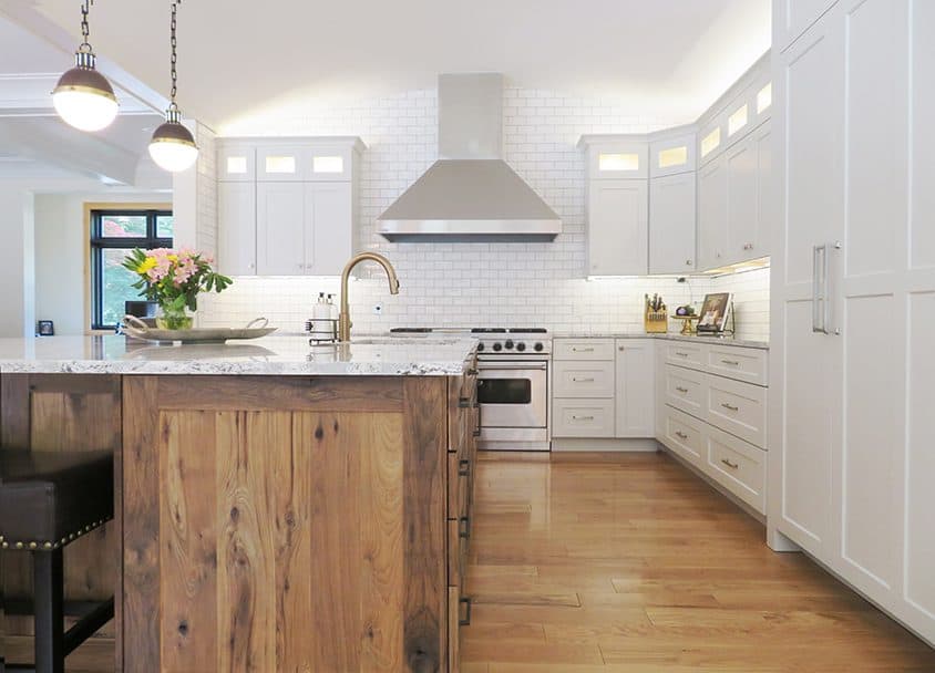 Bright modern kitchen with white cabinets, wooden island, stainless steel appliances, and pendant灯.