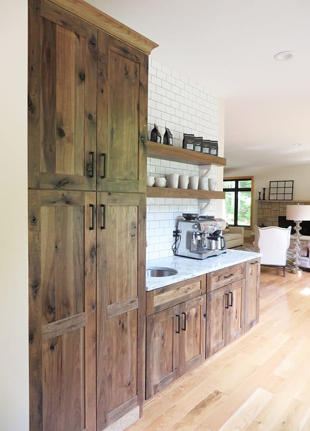 Wooden kitchen cabinets with open shelves and white brick backsplash.