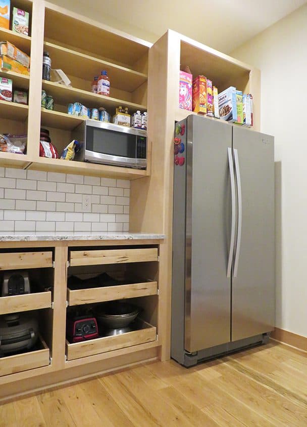 Kitchen with open shelves, microwave, and stainless steel refrigerator.