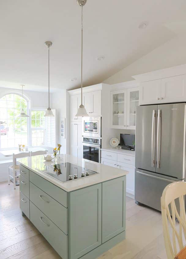 Bright modern kitchen with island, stainless refrigerator, and white cabinetry.