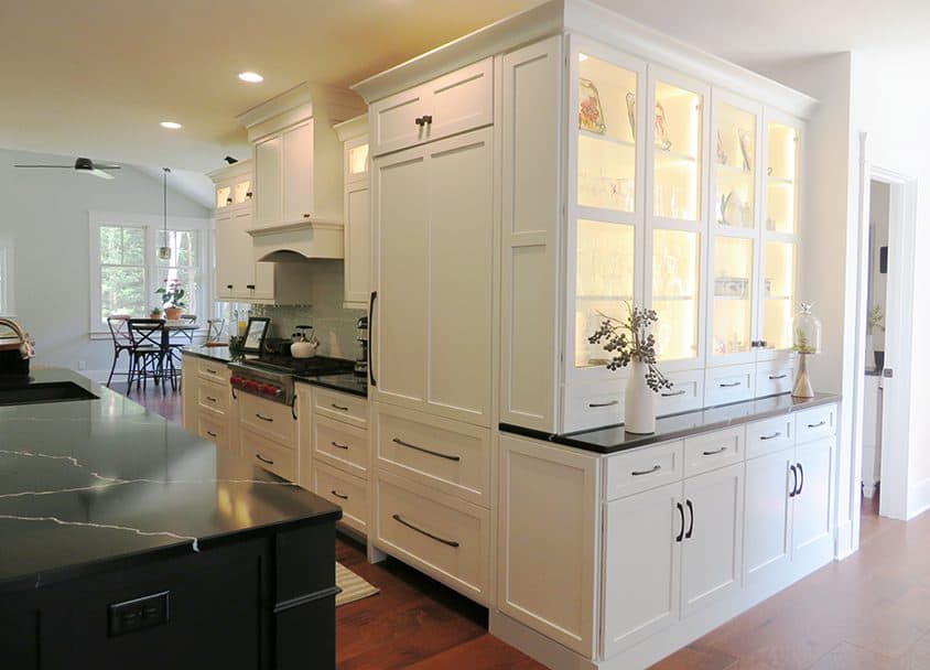 Bright white kitchen with display cabinets and black countertops.