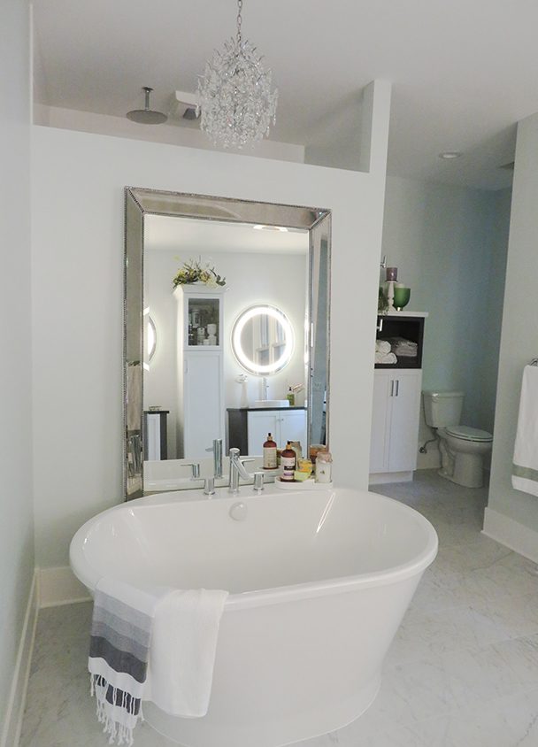 Modern bathroom with freestanding bathtub, large mirror, and circular vanity lights.