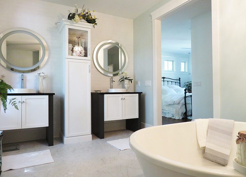 Modern bathroom with two vanities, round mirrors, and a freestanding bathtub.