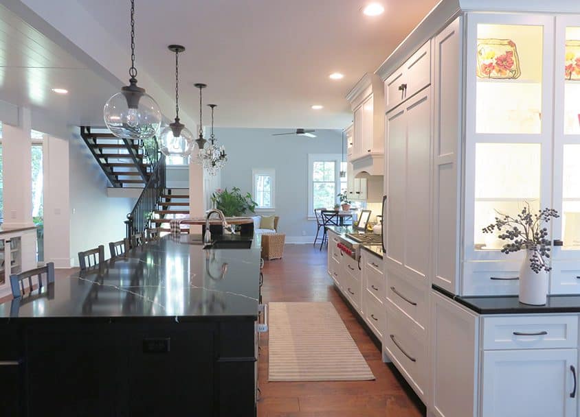 Bright modern kitchen with white cabinets, black island, and large windows.