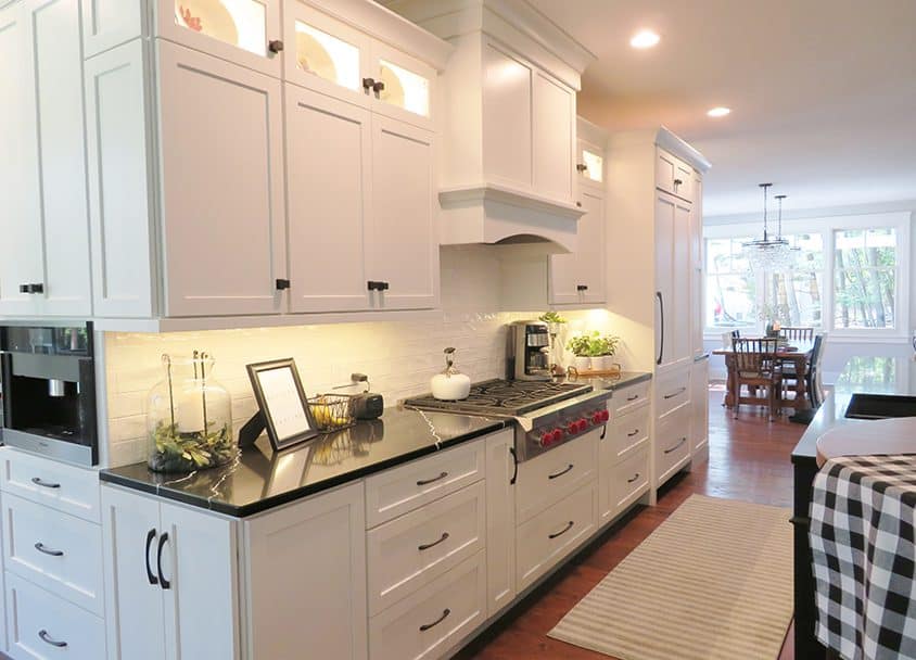 Bright white kitchen with black countertops and modern cabinetry.