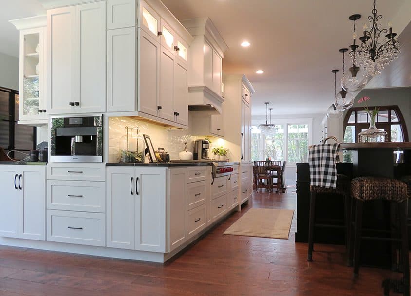 Contemporary white kitchen with cabinetry, appliances, and hardwood flooring.