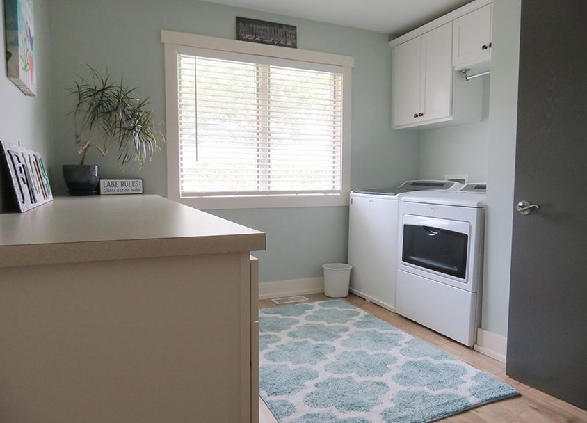 Clean laundry room with washer, dryer, window, and decorative rug.