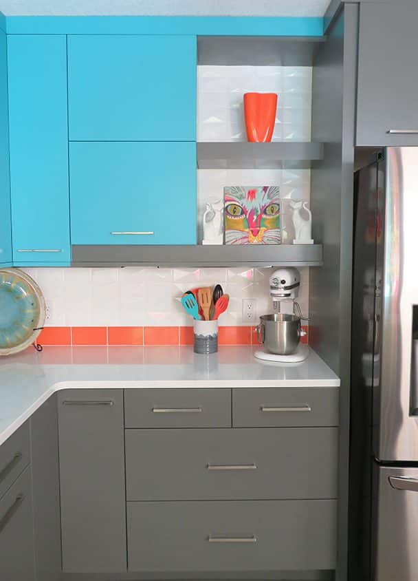 Bright blue and gray kitchen cabinets with decorative items and appliances.