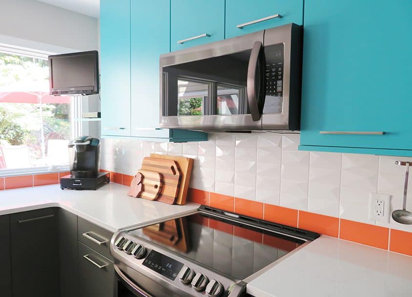 Contemporary kitchen with blue cabinets, stainless steel microwave, and white countertop.